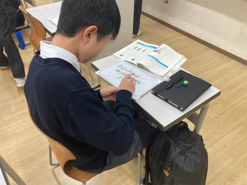 ホワイトボードに自分の考えを書く生徒　画像